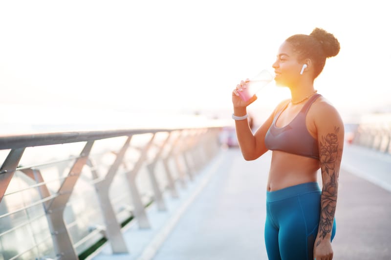 lady drinking water on a bridge